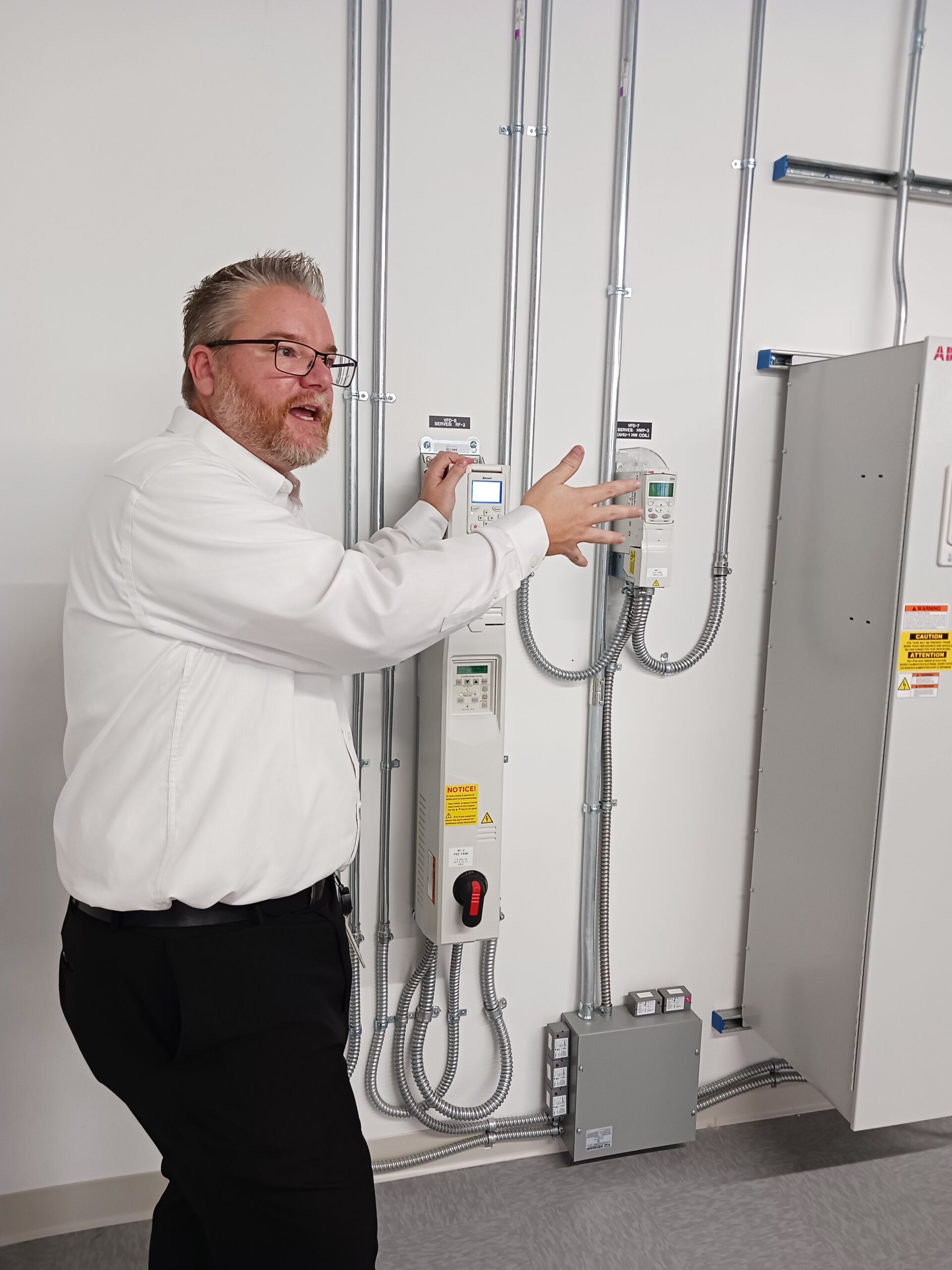 Tim Skell, ABB global HVACR application engineering manager (HVACR stands for heating, ventilation, air conditioning, refrigeration), explains how ABB variable frequency drives (VFDs) are configured with redundancy or bypass for various design risk scenarios to fit different applications and facilities, part of the ABB New Berlin, Wisconsin, mechanical room tour. Courtesy: Mark T. Hoske, Control Engineering, WTWH Media 