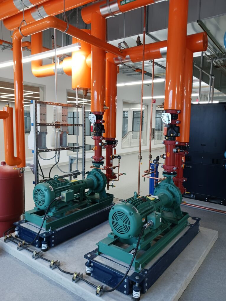 Pumps for hot water return (orange pipes) move up to 250 GPM at 15 HP, part of the ABB New Berlin, Wisconsin, geothermal design, said Tim Skell, ABB global HVACR application engineering manager (HVACR stands for heating, ventilation, air conditioning, refrigeration). Courtesy: Mark T. Hoske, Control Engineering, WTWH Media 