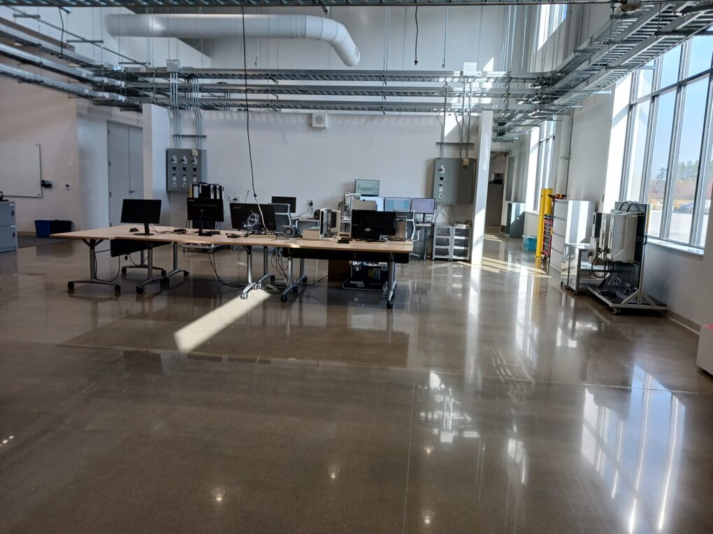 ABB training, classroom and in labs, expands with the ABB advanced manufacturing facility, customer experience center and innovation lab in New Berlin, Wisconsin. Workstations in the middle, electrical panels on the back wall and cart of variable frequency drives (VFDs), right, can help training, along with classes in progress, not shown, said Jeff Fell, application engineering manager. Courtesy: Mark T. Hoske, Control Engineering, WTWH Media